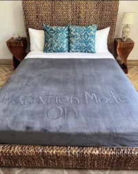 a bed with a blanket that says vacation mode on it